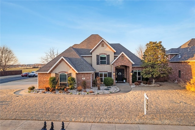 view of front of home with brick siding and a shingled roof