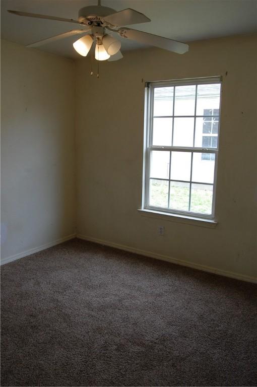 carpeted spare room with ceiling fan and baseboards