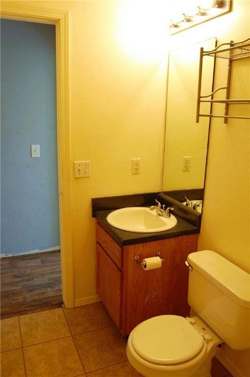 half bath featuring toilet, tile patterned flooring, and vanity