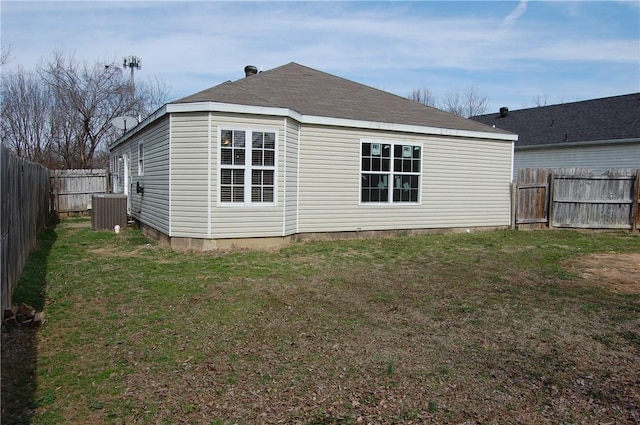 rear view of house featuring a fenced backyard, central AC unit, and a lawn