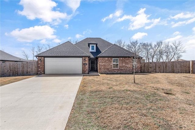 view of front of property with a front yard, driveway, an attached garage, and fence