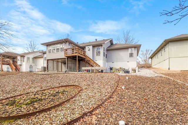 rear view of house featuring stairs and a wooden deck