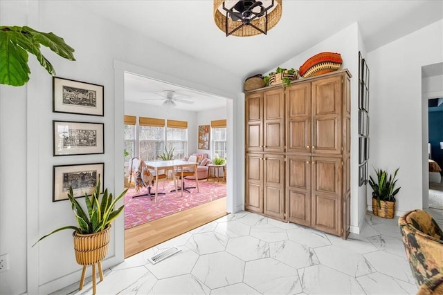 doorway to outside featuring marble finish floor, visible vents, vaulted ceiling, and a ceiling fan