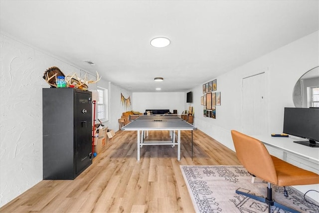 playroom featuring light wood-type flooring and a textured wall