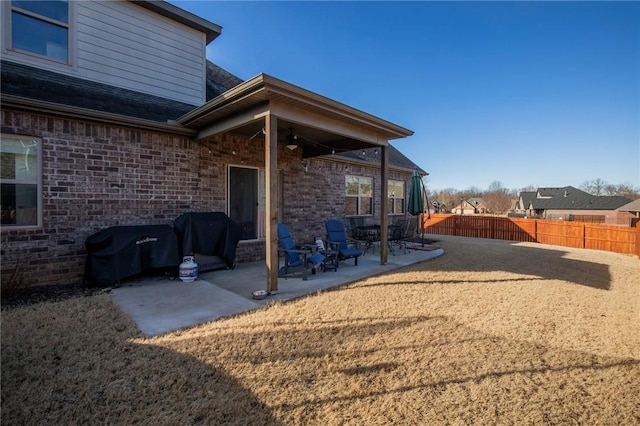 rear view of house featuring brick siding, a patio, and fence