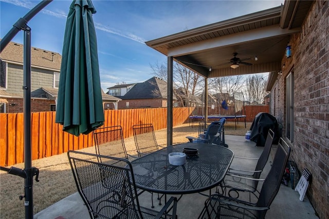 view of patio / terrace with ceiling fan, a fenced backyard, grilling area, outdoor dining space, and a trampoline