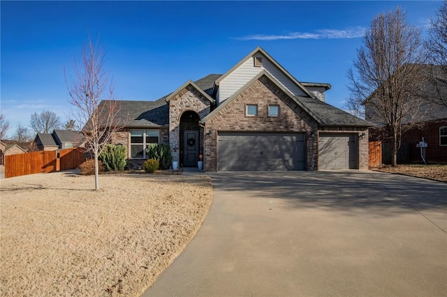 traditional-style house featuring brick siding, an attached garage, fence, stone siding, and driveway