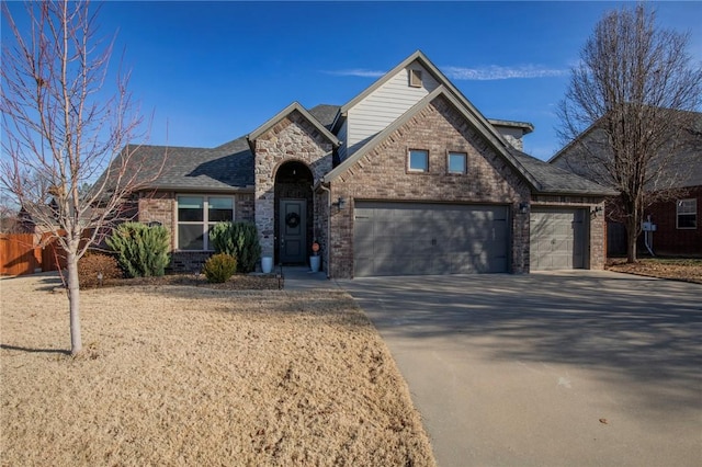 view of front of house featuring a garage, brick siding, a shingled roof, driveway, and stone siding