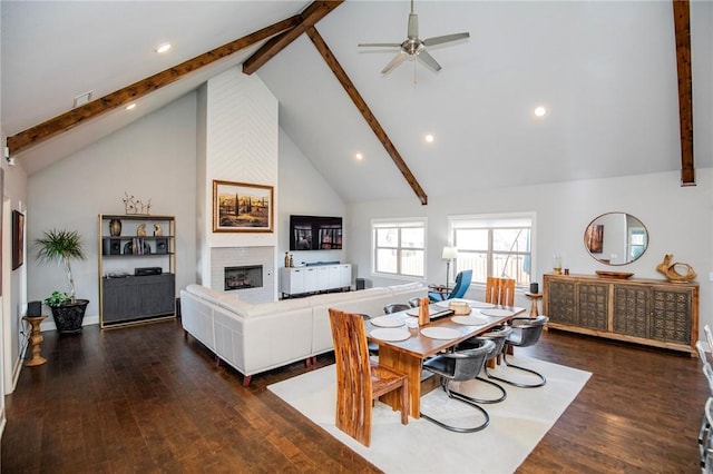 dining area with dark wood finished floors, a large fireplace, and beamed ceiling