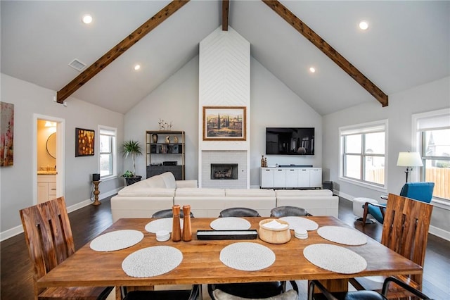 dining room featuring high vaulted ceiling, visible vents, a brick fireplace, beam ceiling, and dark wood finished floors