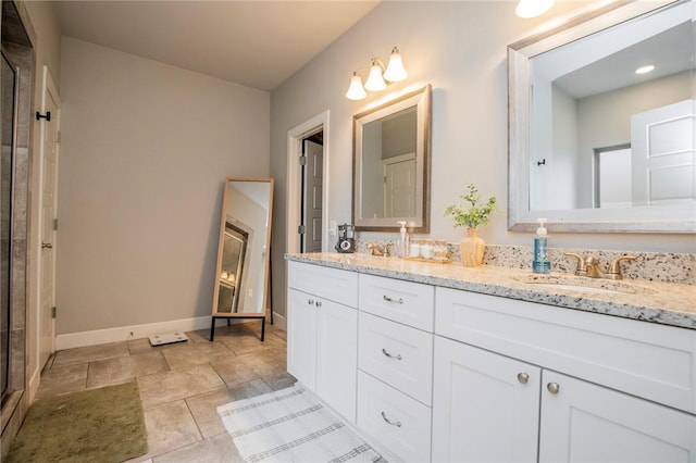 full bathroom with double vanity, a stall shower, a sink, and baseboards