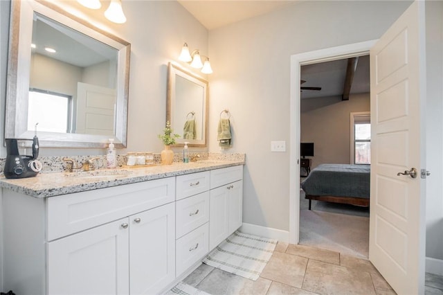 ensuite bathroom featuring connected bathroom, a sink, baseboards, tile patterned floors, and double vanity