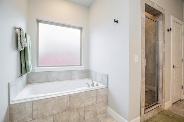 bathroom with a garden tub, a shower stall, and baseboards