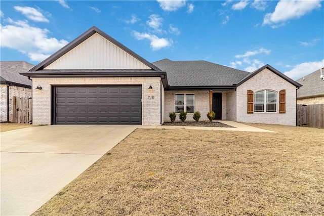 view of front of home with brick siding, concrete driveway, fence, a garage, and a front lawn