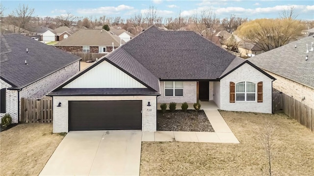 view of front of property featuring driveway, brick siding, an attached garage, and a fenced backyard