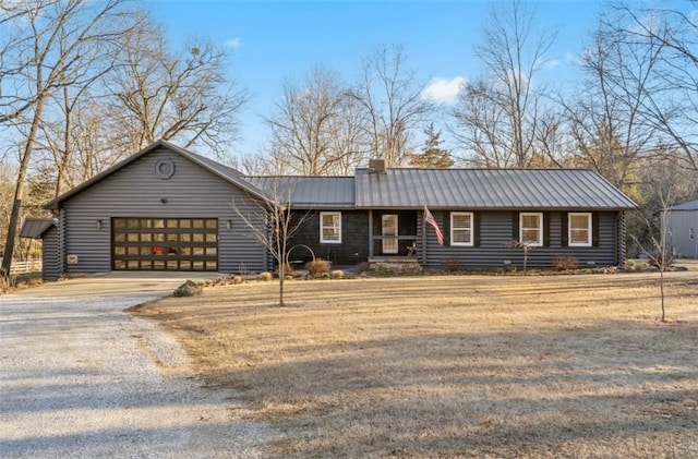 view of front of property with a chimney, an attached garage, a standing seam roof, metal roof, and driveway