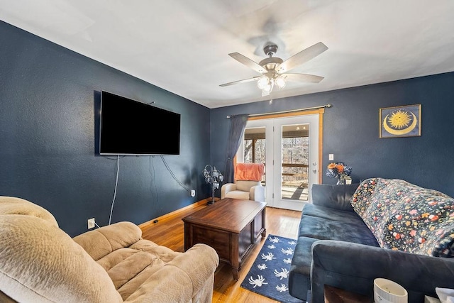 living room with a ceiling fan, baseboards, and wood finished floors