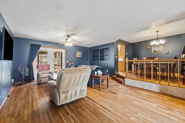 living room with ceiling fan with notable chandelier and wood finished floors