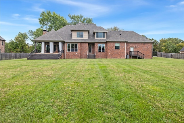 rear view of house featuring brick siding, a lawn, and fence