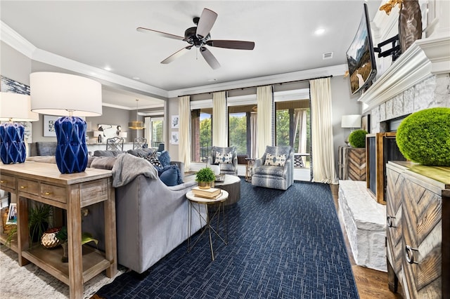 living room featuring a ceiling fan, recessed lighting, crown molding, and a premium fireplace