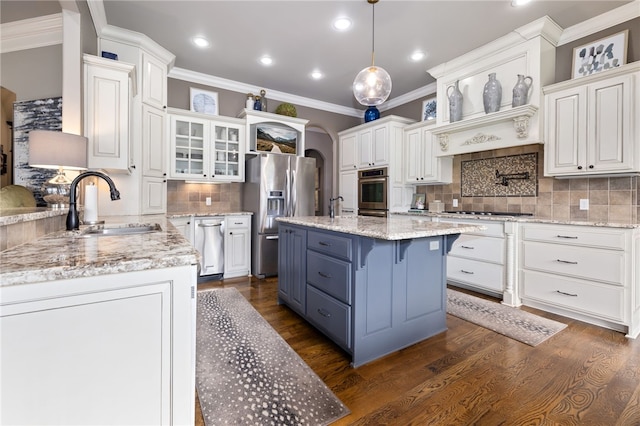 kitchen with arched walkways, a sink, white cabinetry, appliances with stainless steel finishes, and dark wood-style floors