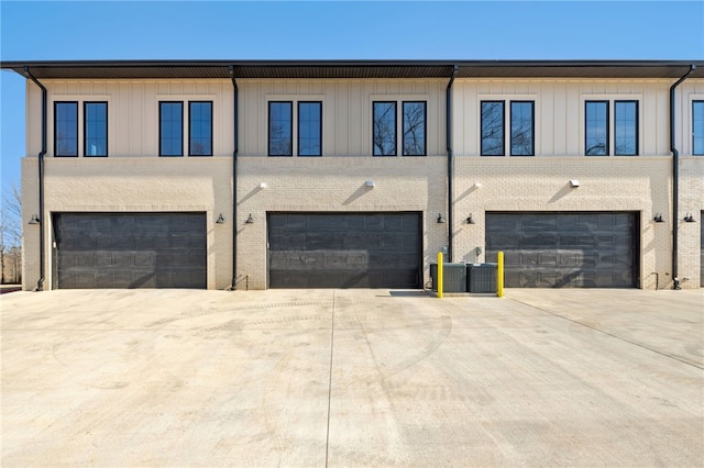 exterior space featuring driveway, a garage, central AC unit, and board and batten siding