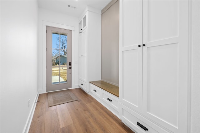 mudroom featuring light wood finished floors, visible vents, and baseboards