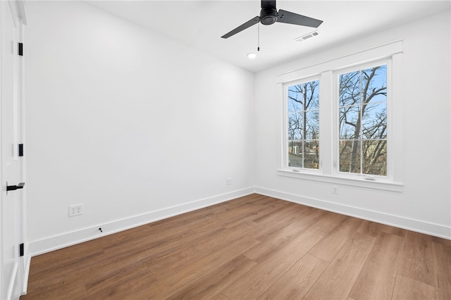 empty room featuring a ceiling fan, baseboards, visible vents, and wood finished floors