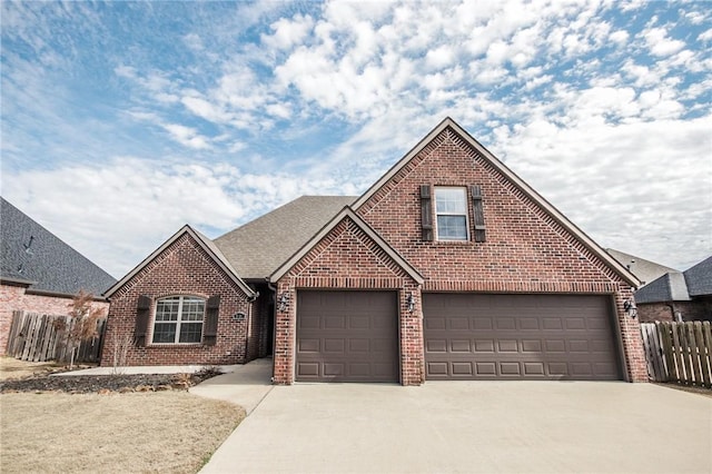 traditional-style home featuring brick siding, roof with shingles, an attached garage, fence, and driveway