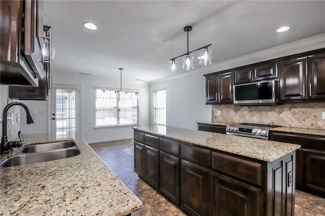 kitchen featuring a sink, appliances with stainless steel finishes, backsplash, a center island, and plenty of natural light