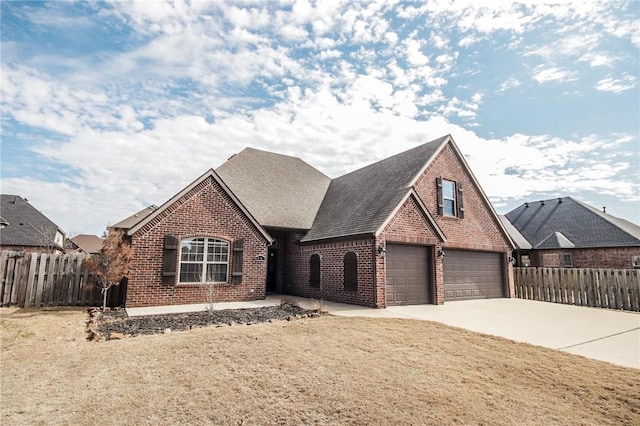 view of front facade with driveway, an attached garage, fence, and brick siding