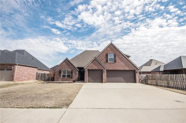 view of front facade with driveway, brick siding, a shingled roof, and fence