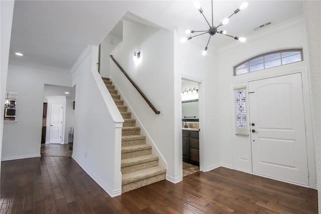 entrance foyer with dark wood-style floors, visible vents, and crown molding