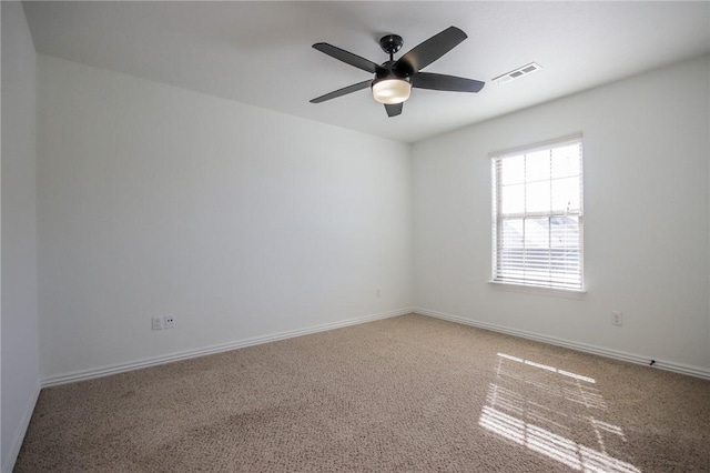 carpeted empty room with ceiling fan, visible vents, and baseboards