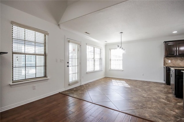 interior space featuring a textured ceiling, wood finished floors, visible vents, baseboards, and ornamental molding