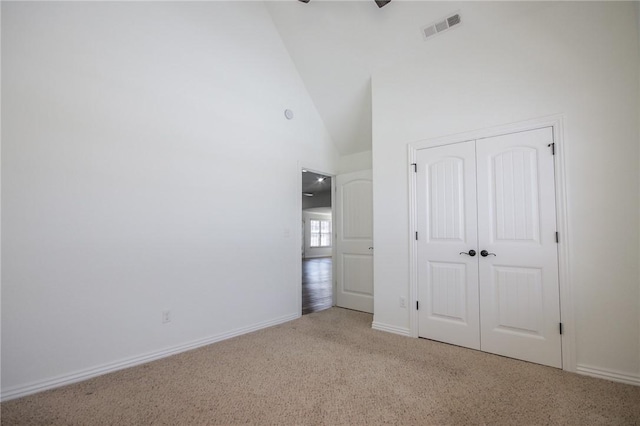 unfurnished bedroom with high vaulted ceiling, visible vents, baseboards, a closet, and carpet