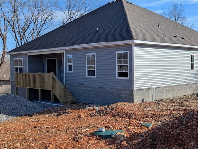 back of house featuring roof with shingles and stairway