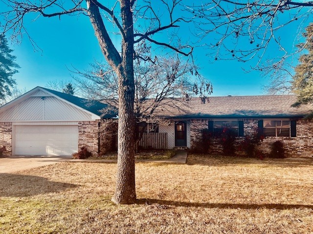 ranch-style home featuring a front lawn, brick siding, driveway, and an attached garage