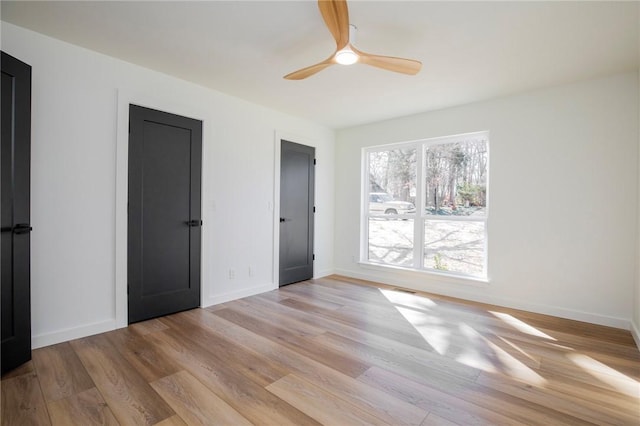 unfurnished bedroom with baseboards, ceiling fan, and light wood finished floors