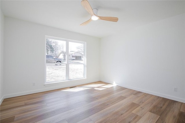 empty room featuring a ceiling fan, baseboards, and wood finished floors