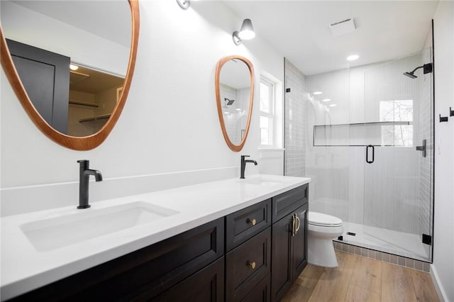 bathroom featuring toilet, a shower stall, a sink, and wood finished floors