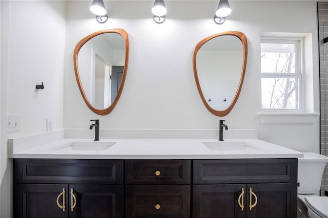 bathroom with double vanity, a sink, and toilet