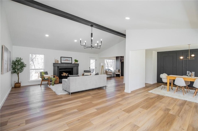 living room with light wood-type flooring, a fireplace, beamed ceiling, and a notable chandelier