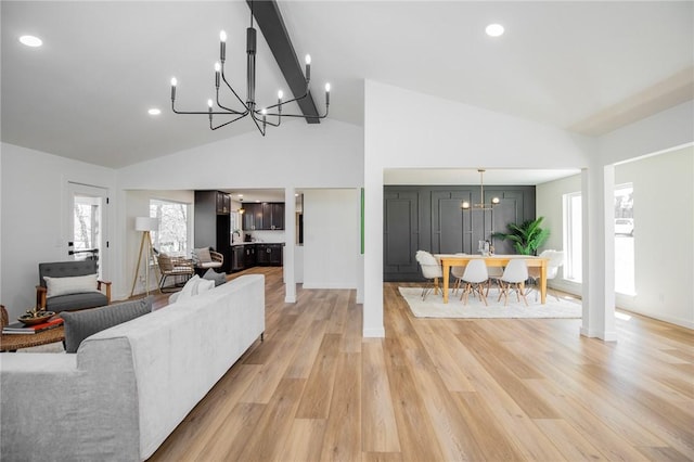 living area featuring beam ceiling, a notable chandelier, recessed lighting, high vaulted ceiling, and light wood-type flooring