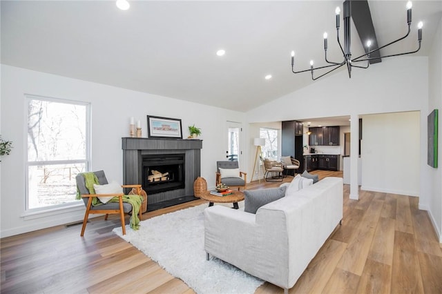 living room with a fireplace with flush hearth, baseboards, light wood-style flooring, and recessed lighting