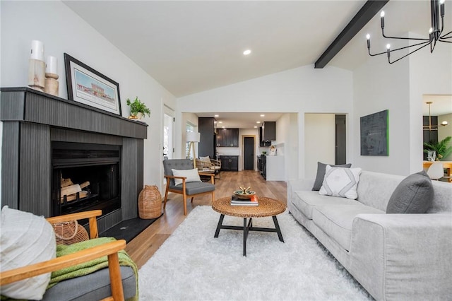 living area with light wood finished floors, a fireplace with flush hearth, beamed ceiling, high vaulted ceiling, and a notable chandelier