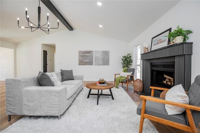 living area with lofted ceiling with beams, a fireplace with raised hearth, a chandelier, recessed lighting, and wood finished floors