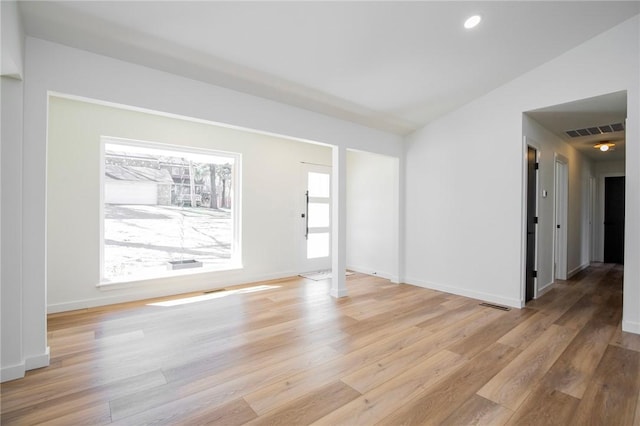 interior space featuring light wood-type flooring, baseboards, visible vents, and vaulted ceiling