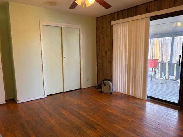 unfurnished bedroom with access to outside, a closet, ceiling fan, and wood finished floors