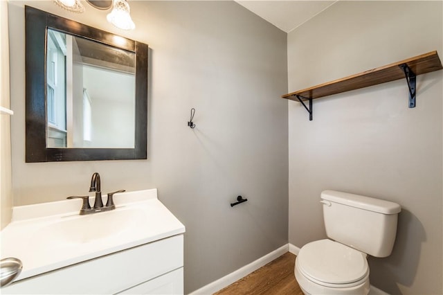 half bathroom featuring vanity, wood finished floors, toilet, and baseboards